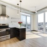 View of open concept kitchen, floor-to-ceiling windows and balcony door